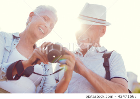 Radiant senior couple looking at photos on camera 42471665