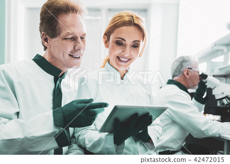 Blonde-haired biologist smiling while cooperating with colleagues Blonde-haired biologist smiling while cooperating with colleagues 42472015