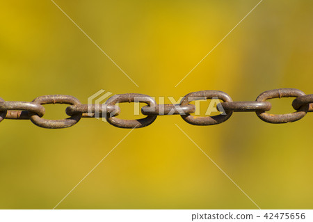 Old metal chain on a blurred yellow background Old metal chain on a blurred yellow background 42475656