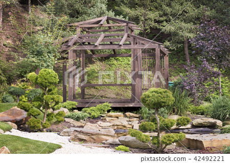 Wooden arbor surrounded by bonsai trees, pines  42492221