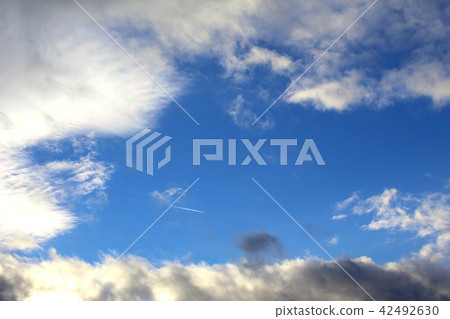 blue sky with clouds and a condensation trail 42492630