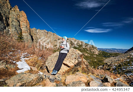 Woman tourist on a trail in Rocky Mountains Woman tourist on a trail in Rocky Mountains 42495347