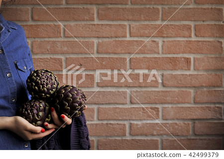 Artichokes are fresh in the hands of women. Bouquet from vegetables. Healthy Italian food. 42499379