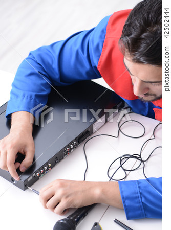 Man repairman repairing dvd player at service center Man repairman repairing dvd player at service center 42502444
