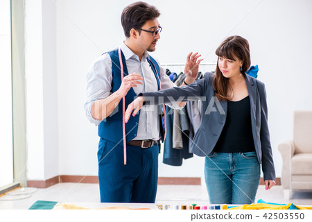 Professional tailor taking measurements for formal suit 42503550