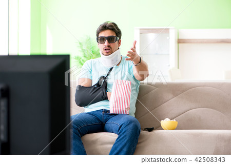Man with neck and arm injury watching tv Man with neck and arm injury watching tv 42508343