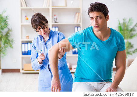 Doctor checking nerve reflexes with hammer 42509017