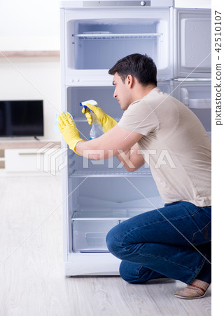Man cleaning fridge in hygiene concept 42510107