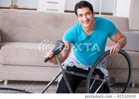 Young man repairing bicycle at home Young man repairing bicycle at home 42510930