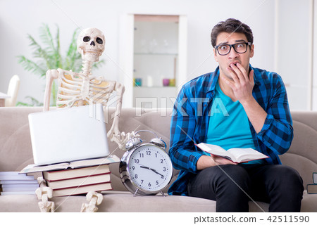 Student studying with skeleton preparing for exams 42511590