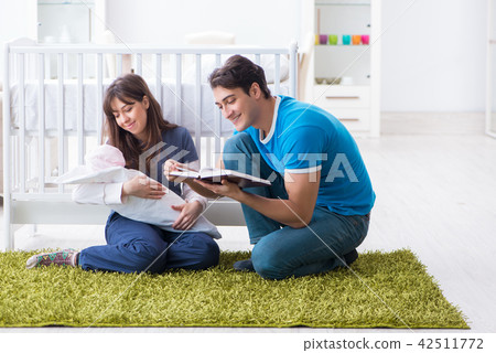 Young parents with their newborn baby sitting on the carpet  42511772