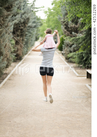 Little girl walking on the shoulders of her mother 42512269