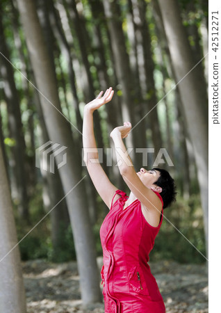 Woman dressed in red, meditating in the forest Woman dressed in red, meditating in the forest 42512271