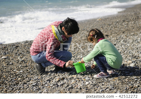 Mother and little girl having fun on the beach in winter 42512272