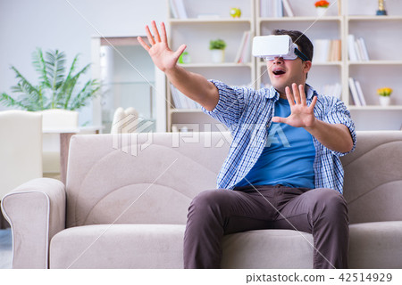 Man with virtual reality glasses playing at home Man with virtual reality glasses playing at home 42514929