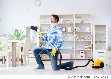 Injured man with neck injury vacuum cleaning house Injured man with neck injury vacuum cleaning house 42516871