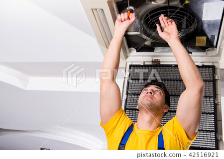Repairman repairing ceiling air conditioning unit Repairman repairing ceiling air conditioning unit 42516921