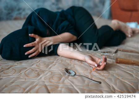 Female druggy with syringe in hand lies in bed Female druggy with syringe in hand lies in bed 42519474