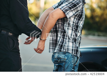 Policeman arrests the car thief on road Policeman arrests the car thief on road 42519804