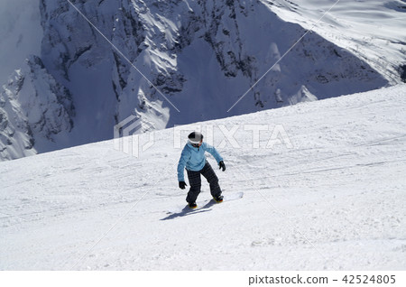 Snowboarder downhill on ski slope in high snowy mountains 42524805