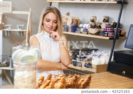 Pretty girl with blonde hair choosing croissants in local shop. Pretty girl with blonde hair choosing croissants in local shop. 42525163