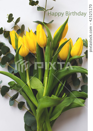 Beautiful yellow tulips on a white table, inscription happy birthday Beautiful yellow tulips on a white table, inscription happy birthday 42525170