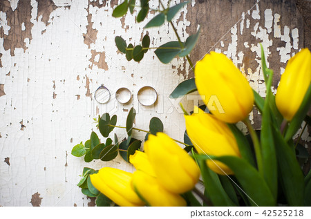 wedding rings with yellow tulips on old white table wedding rings with yellow tulips on old white table 42525218