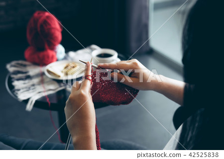 Close up shot of young woman hands knitting a red scarf handicra 42525838