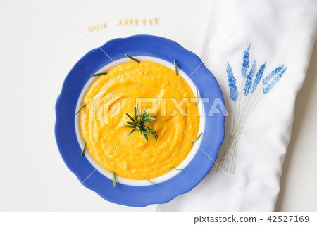 pumpkin soup in a blue plate on a napkin with flowers pumpkin soup in a blue plate on a napkin with flowers 42527169
