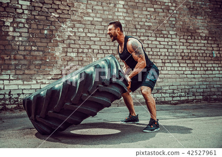 Muscular fitness man moving large tire. Muscular fitness man moving large tire. 42527961