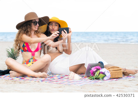 Happy women taking photo on sand beach in summer. 42530371
