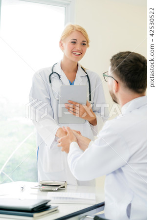 Doctor at hospital shakes hand with another doctor Doctor at hospital shakes hand with another doctor 42530522