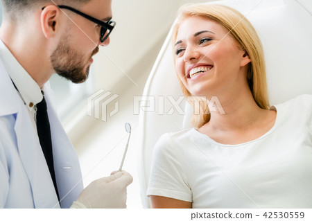 Young dentist talks with patient in dental clinic. 42530559