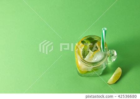 Homemade sparkling cold alcoholic mojito from natural citrus fruits with plastic straws on a green Homemade sparkling cold alcoholic mojito from natural citrus fruits with plastic straws on a green 42536680