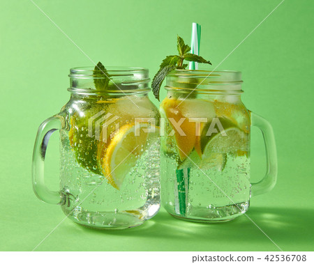 Cold natural alcoholic mojito with bubbles of air. Two glass mason jar with handmade cocktail on a Cold natural alcoholic mojito with bubbles of air. Two glass mason jar with handmade cocktail on a 42536708