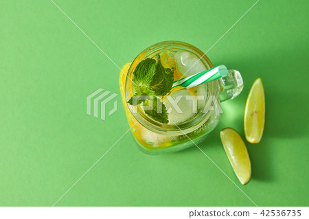 Refreshing natural non-alcoholic cocktail in glass jar with ice cubes, slices of lime and lemon Refreshing natural non-alcoholic cocktail in glass jar with ice cubes, slices of lime and lemon 42536735