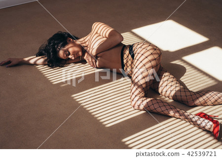 Sexy woman in black pantyhose lying on floor touching lips by finger. Sexy woman in black pantyhose lying on floor touching lips by finger. 42539721
