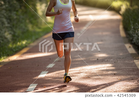 Healthy woman runner running on park road   42545309