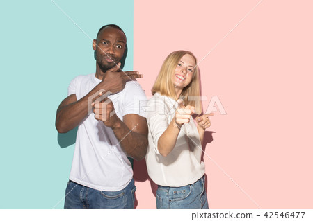 Beautiful female and male portrait on pink and blue studio backgroud. The young emotional couple 42546477