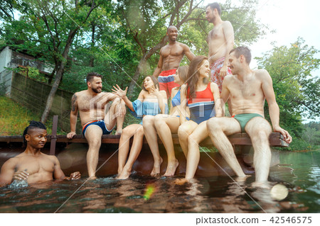 Enjoying river party with friends. Group of beautiful happy young people at the river together Enjoying river party with friends. Group of beautiful happy young people at the river together 42546575