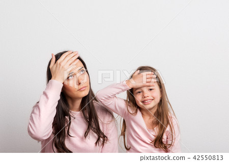 A small girl and her mother in a studio, hands on their forehead. A small girl and her mother in a studio, hands on their forehead. 42550813