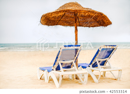 Focus on parasol. Sunbeds on snow-white sand 42553314