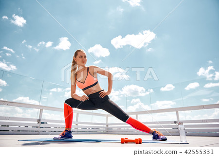 Concentrated lady is having workout on roof Concentrated lady is having workout on roof 42555331
