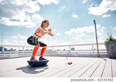 Joyful woman is exercising with fitness equipment on sunny terrace Joyful woman is exercising with fitness equipment on sunny terrace 42555492