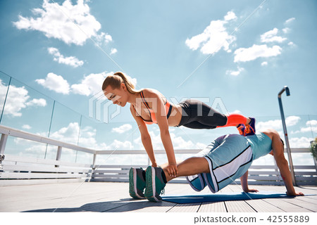 Slender woman is doing fitness with boyfriend assistance outdoor 42555889