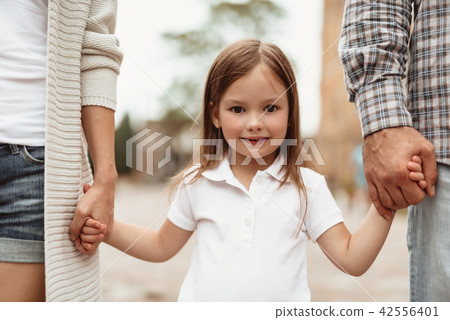 Cheerful kid walking with parents outside 42556401