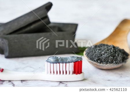 Toothpaste by activated charcoal powder on table