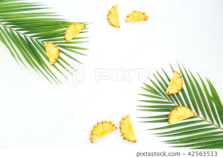 Frame with sliced pineapple fruits and palm leaves 42563513