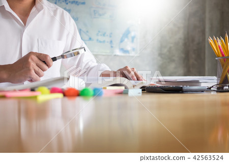 teenage man sitting by wooden table reading and writting on note teenage man sitting by wooden table reading and writting on note 42563524