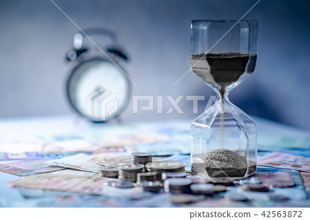 Hourglass and currency on table, Time Investment 42563872